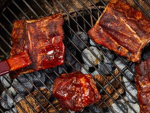 Barbecue ribs and meat on a grill with sauce being applied