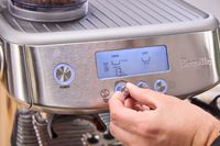 A person turns a dial on the front of the Breville The Barista Pro Espresso Machine