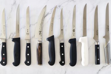 A selection of boning knives on a marble countertop