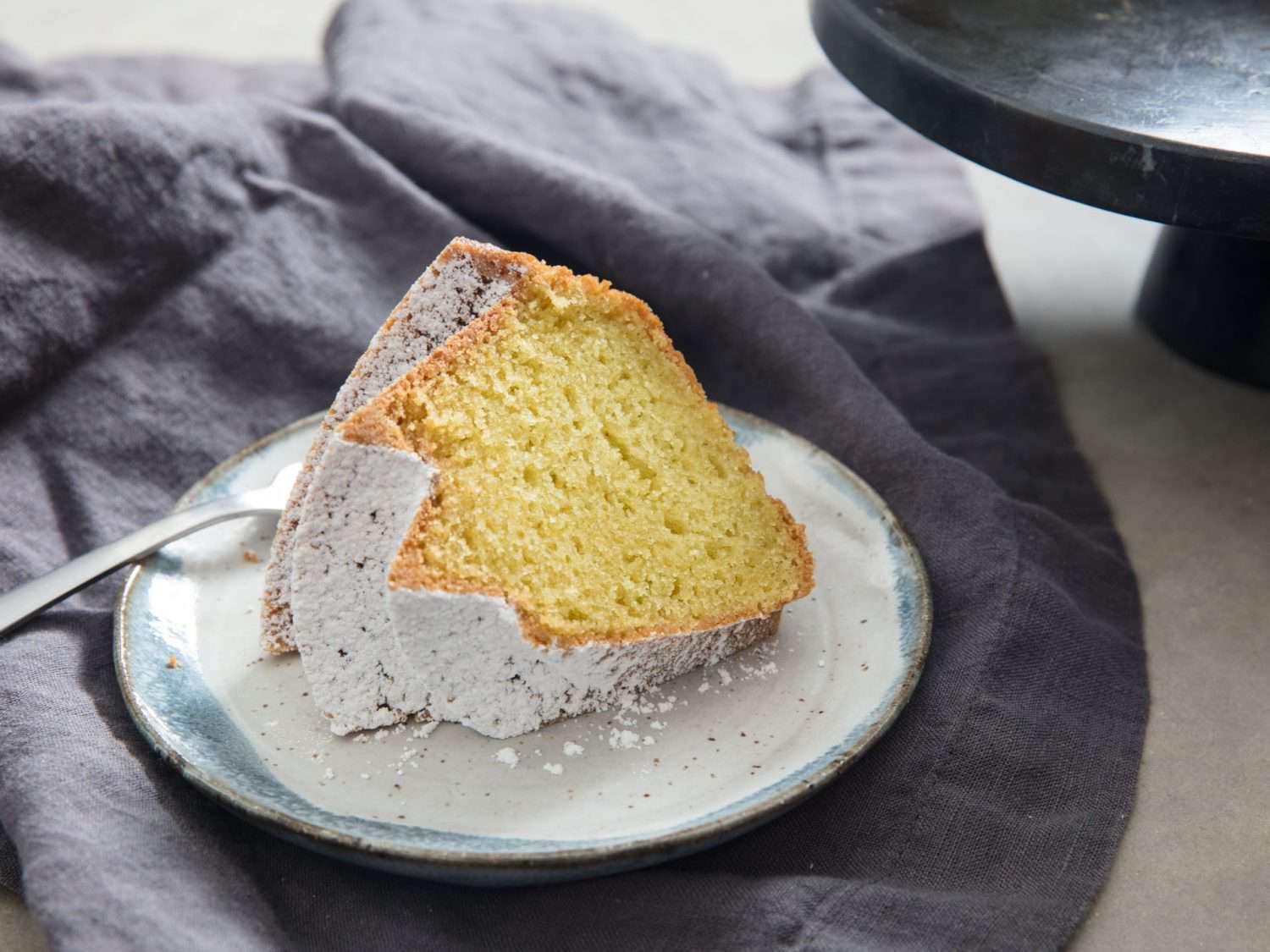 A slice of Jubilee bundt cake dusted with powdered sugar on a white plate.