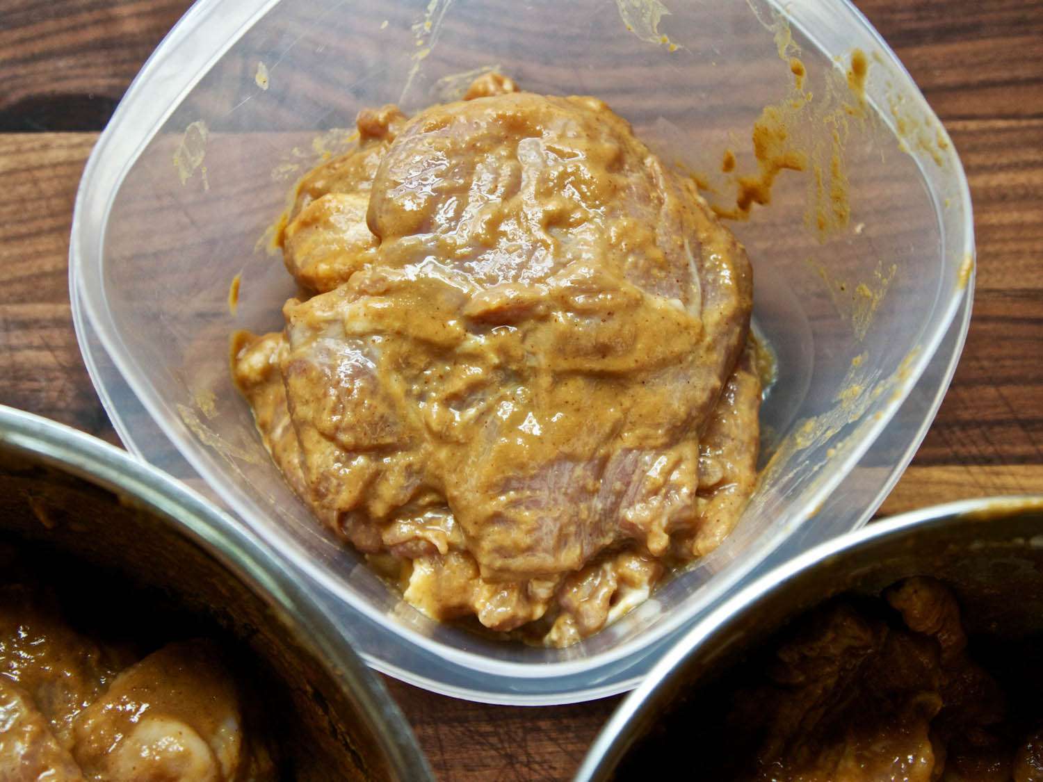 Closeup of marinade-coated slices of turkey, stacked in a plastic storage container.