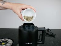 green coffee being loaded into a coffee roaster