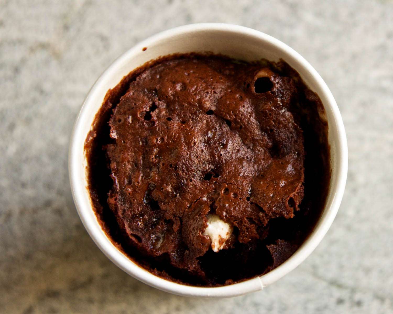 Overhead closeup of a microwave rocky road sponge cake, served in a ramekin.