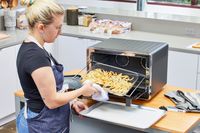 A person tossing fries cooking in the KitchenAid Dual Convection Countertop Oven with Air Fryer