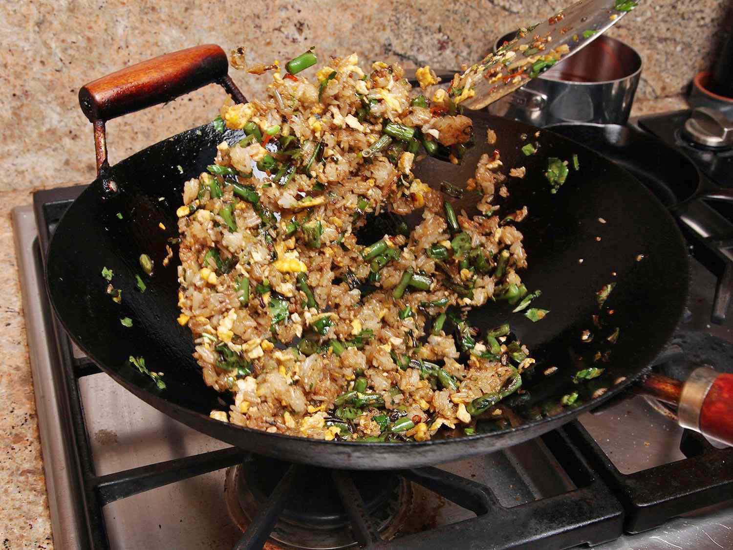 Once the egg is fried and then scrambled and broken up, the mixture is tossed to in the wok to combine.