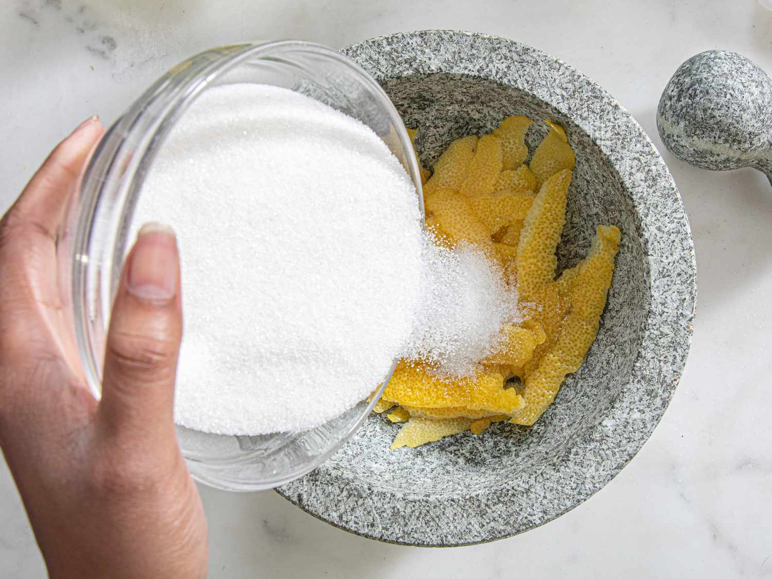 Pouring sugar onto the lemon peels.