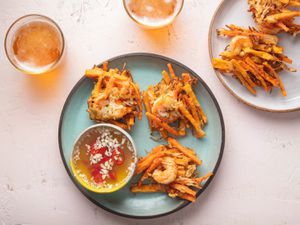 Filipino Ukoy fritters on blue plate with dipping sauce and beer on the side
