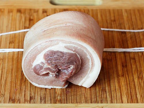 A rolled pork belly, ready to be tied with cut lengths of butcher twine.