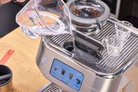 A person pours water into the Breville The Oracle Dual Boiler Espresso Machine