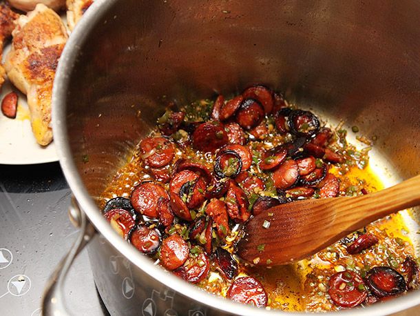 Sliced chorizo browning until it is crisp and nearly charred on the edges.