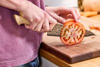 A person slicing a tomato with the Zwilling Kanren 8 Inch Chef's Knife
