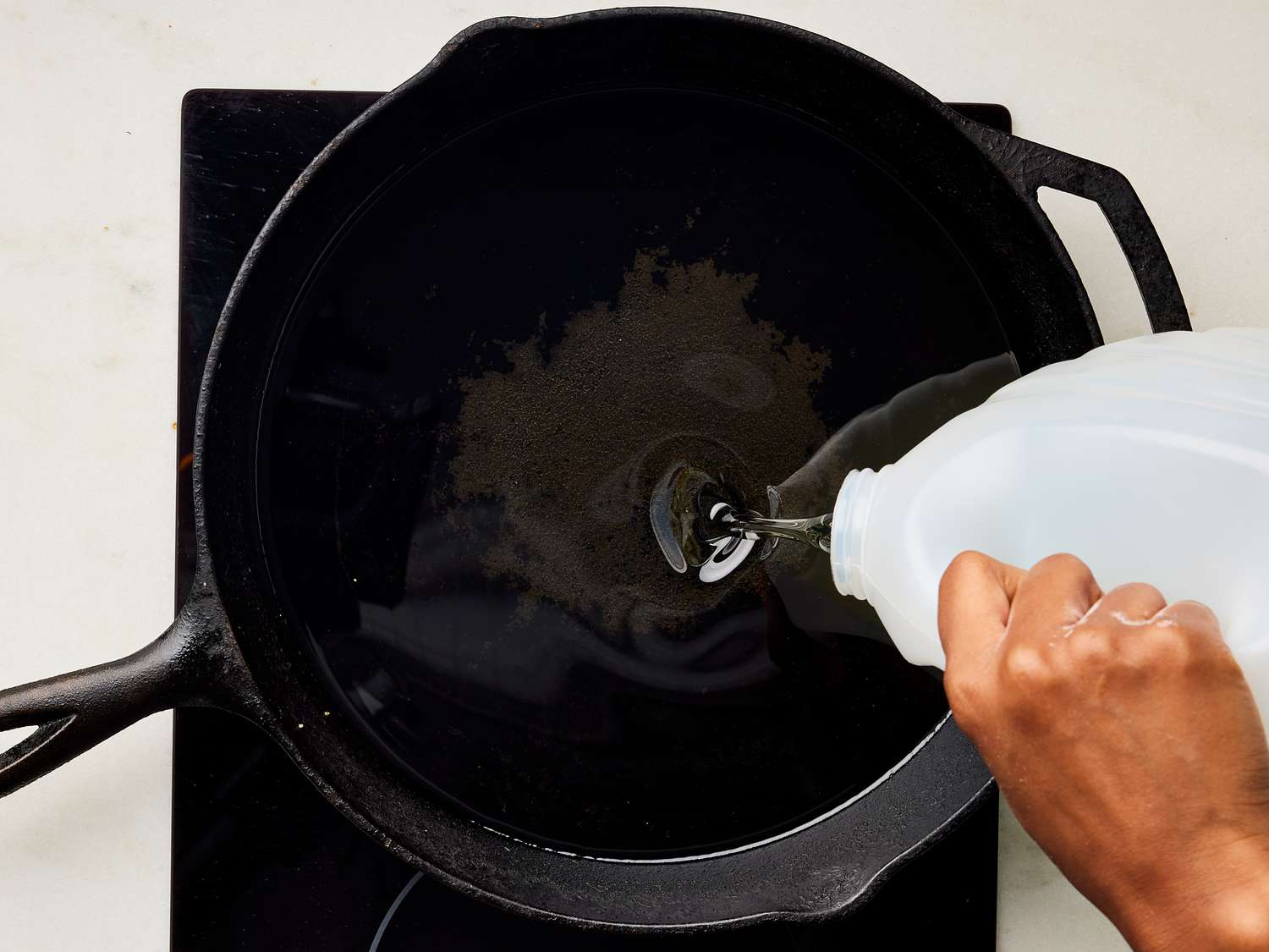Oil being poured into a cast iron skillet 