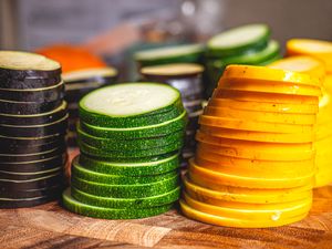 Stacked slices of green zucchini and yellow squash on a cutting board, arranged neatly