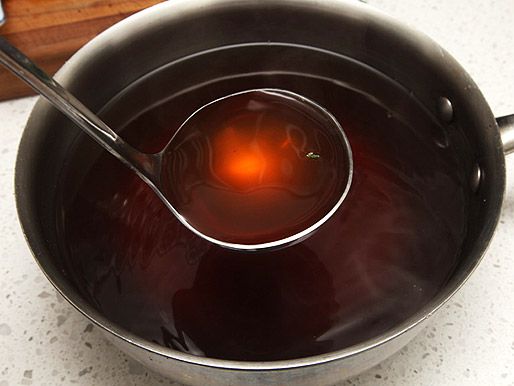 Dark clear vegetable stock ladled out of pot