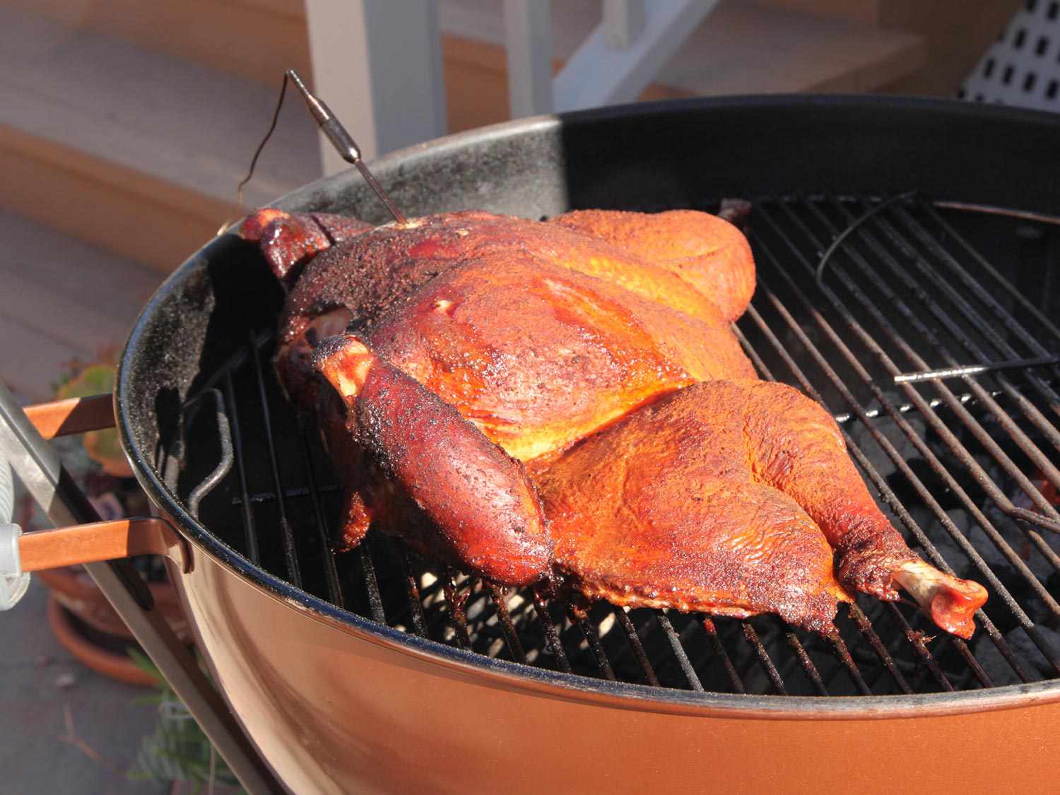 Turkey is nearly cooked through. The skin looks reddish brown from exposure to smoke.
