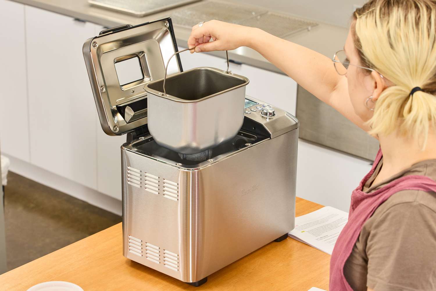 A person placing a basket inside of the Breville Custom Loaf Bread Maker