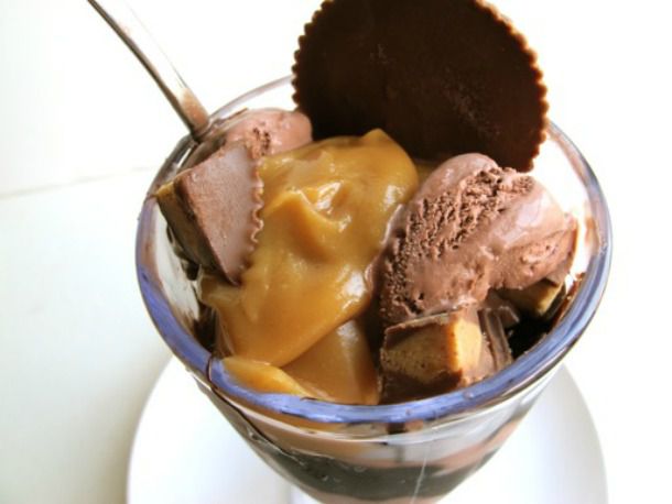 Closeup of a Reese's peanut butter sundae, served in a glass ice cream bowl.