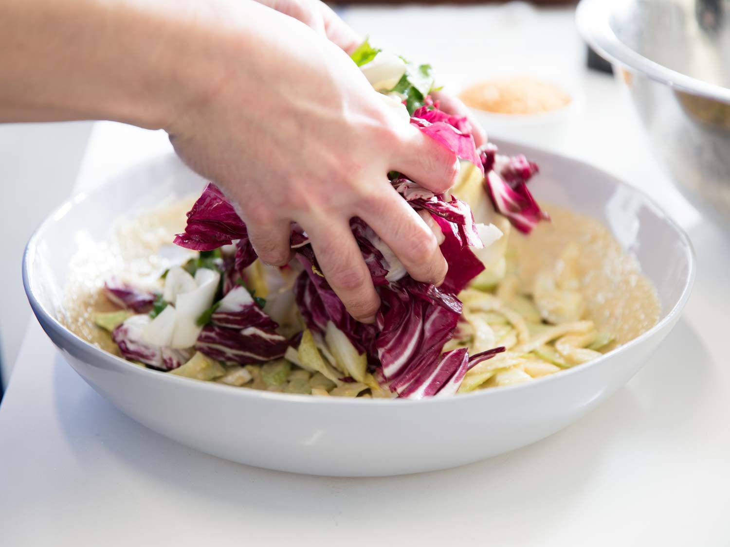 Layering dressed greens on top of fennel and celery in anchovy dressing. 