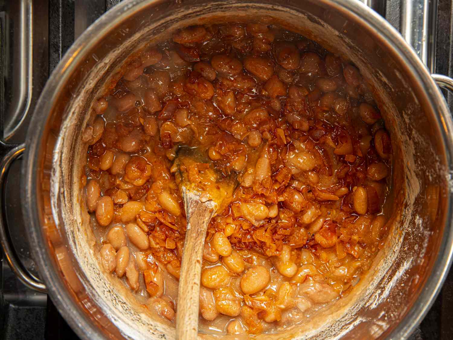 Overhead view of stirring onion mixture into beans