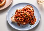 British-style baked beans on a piece of white bread which is placed on a blue ceramic plate on a stone background.