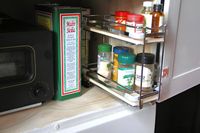 A kitchen with a tin of olive oil a toaster oven and a spice rack featuring various containers and bottles