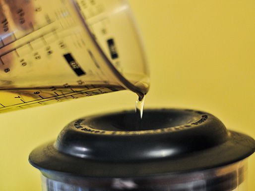 Slowly drizzling oil into a blender containing creamy French dressing. 