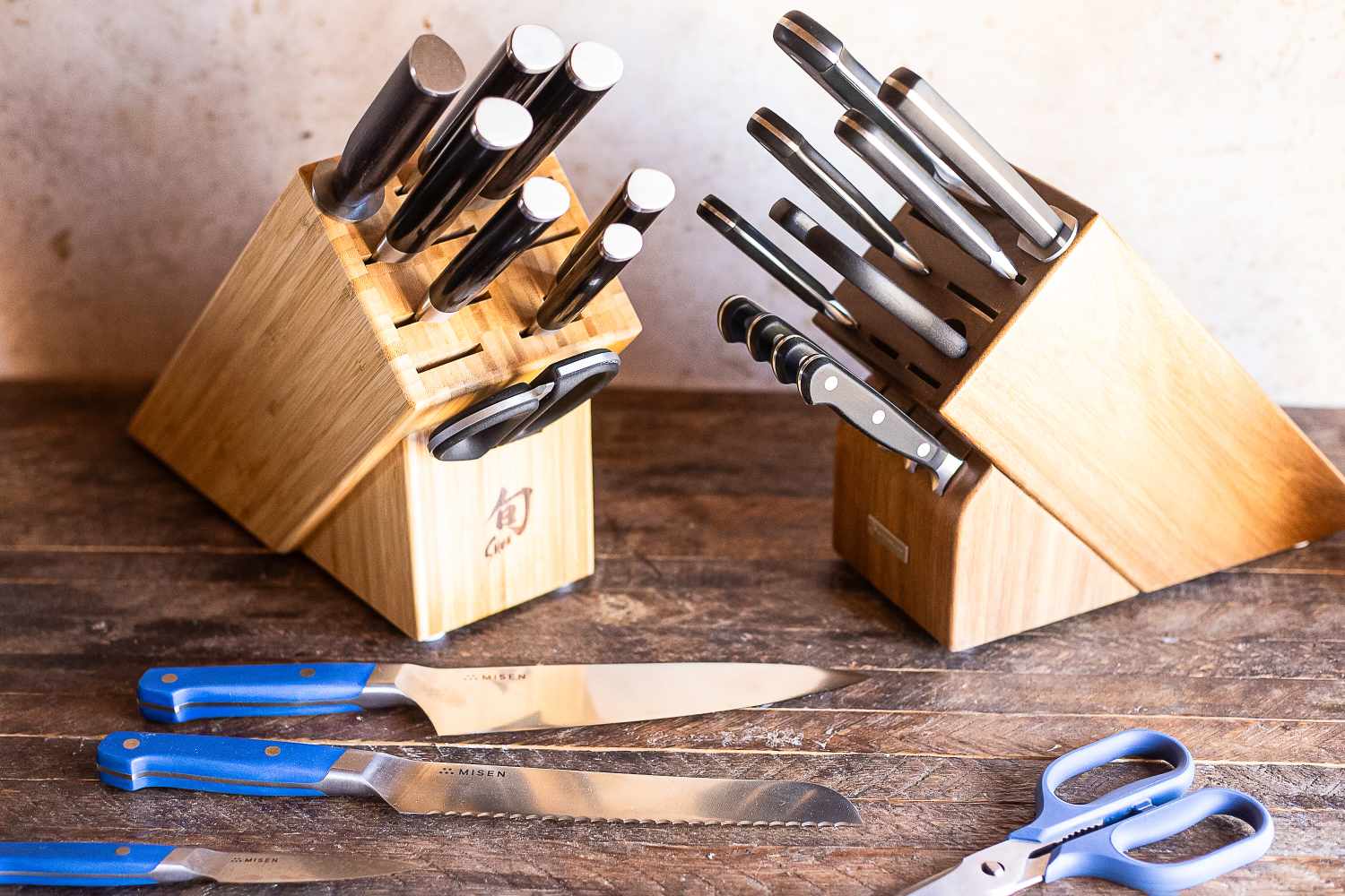 Two wooden knife blocks with various knives and kitchen shears on a wooden surface