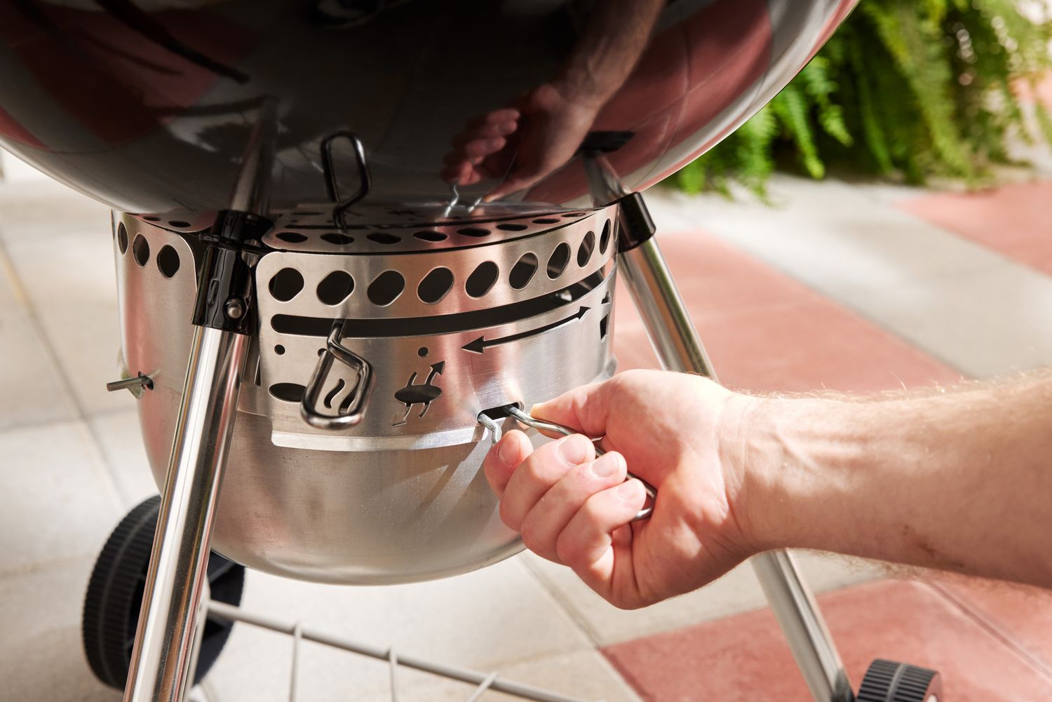 A person adjusting the damper of a charcoal grill