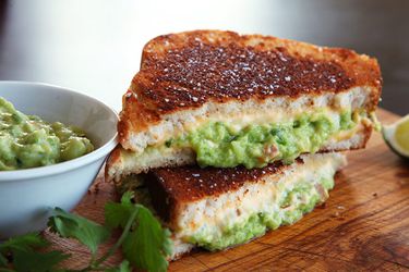 Cross-section view of two halves of a grilled cheese sandwich with guacamole