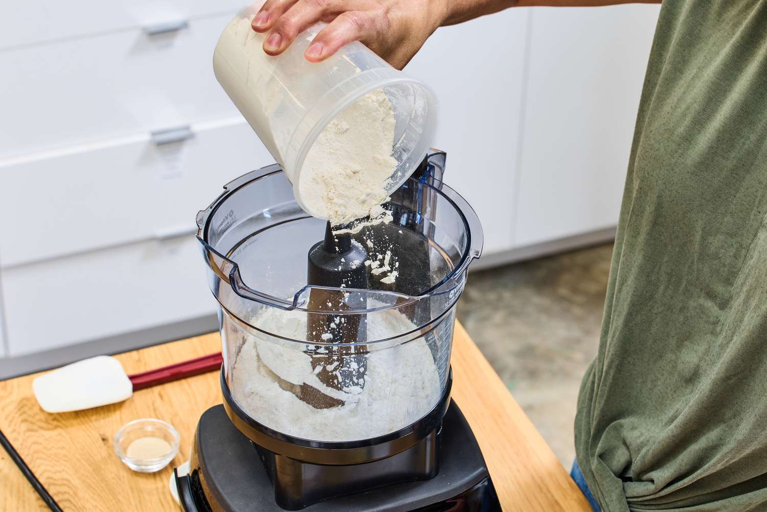 A person pours flour into the Vitamix 12-Cup Food Processor Attachment