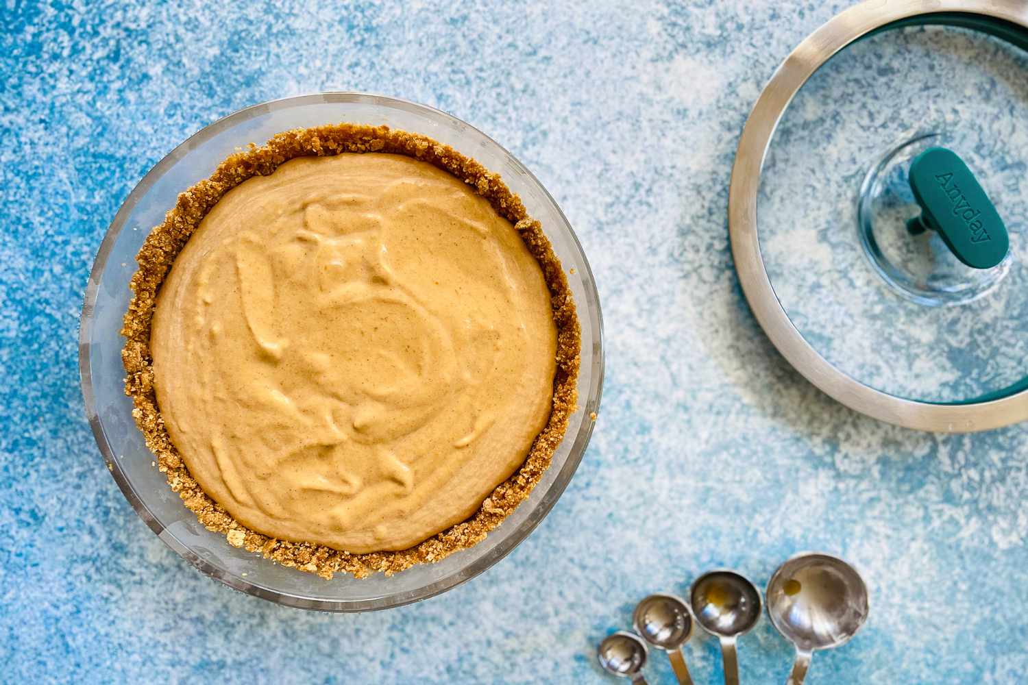 a pumpkin pie in an Anyday dish that's set on a blue countertop