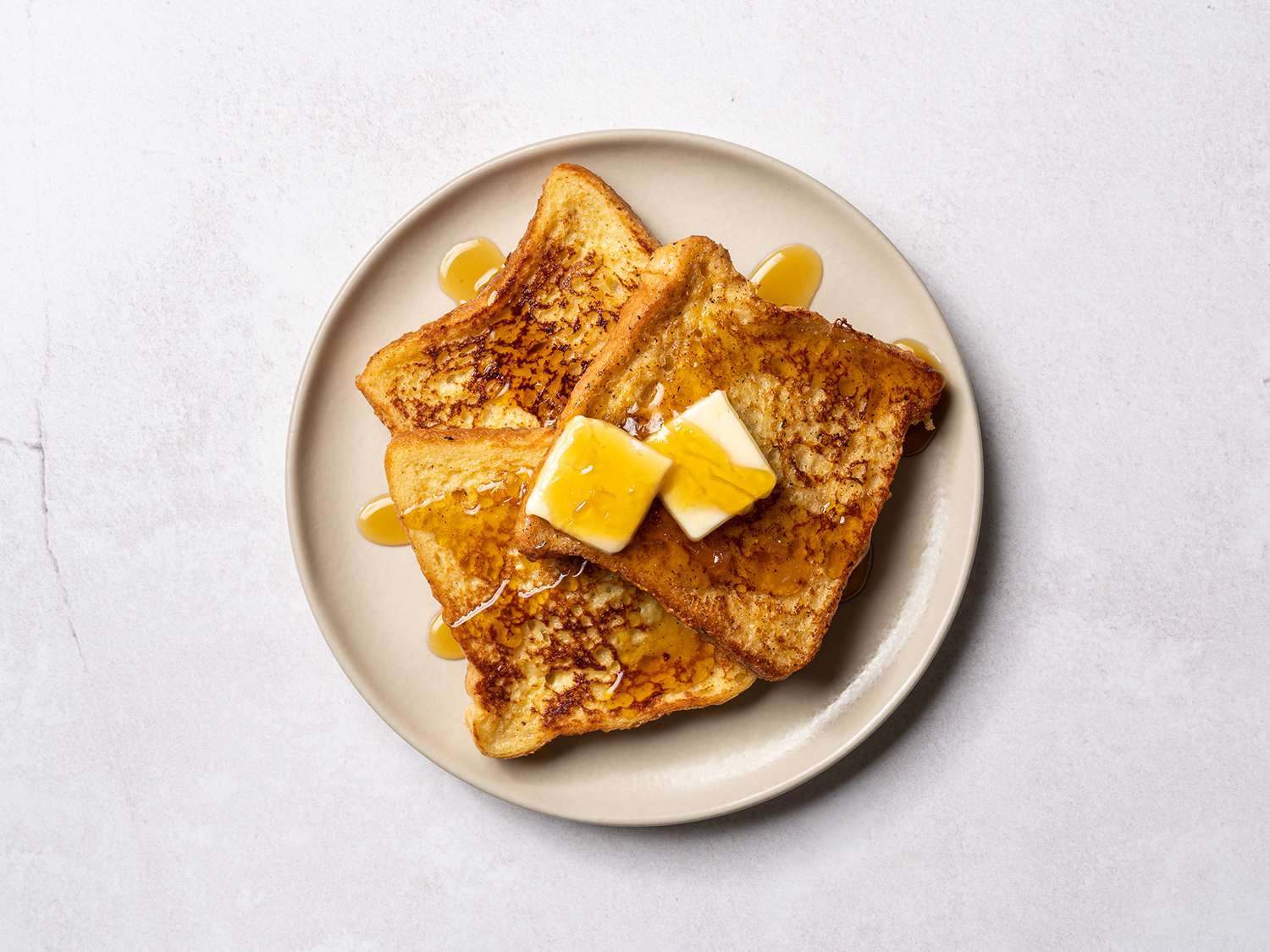 A serving of French toast topped with butter and maple syrup.