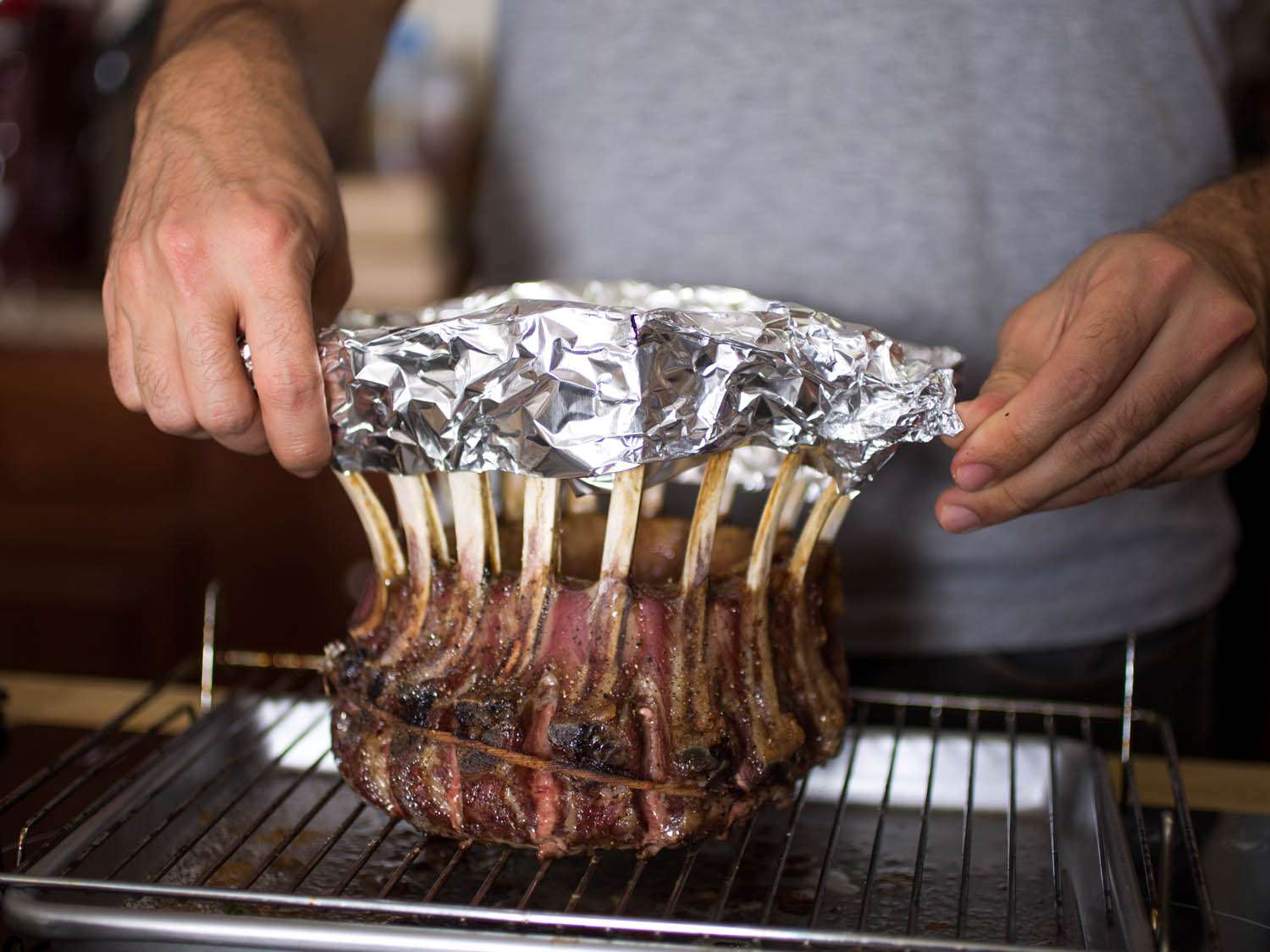 Covering the exposed bones in a crown roast of lamb with foil.