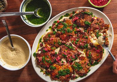 Platter of smashed double sauce potatoes with garnishes on a wooden table