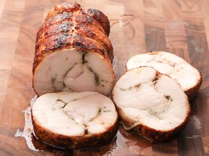 Roast turkey porchetta (turchetta) sliced and on a wooden cutting board.