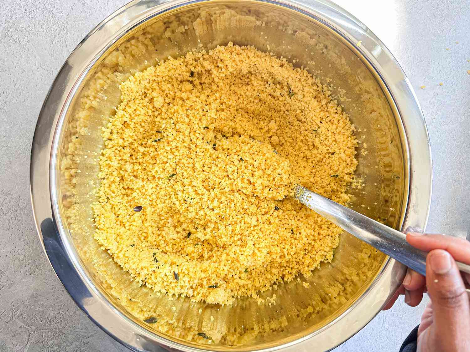 A bowl of couscous being stirred with a spoon