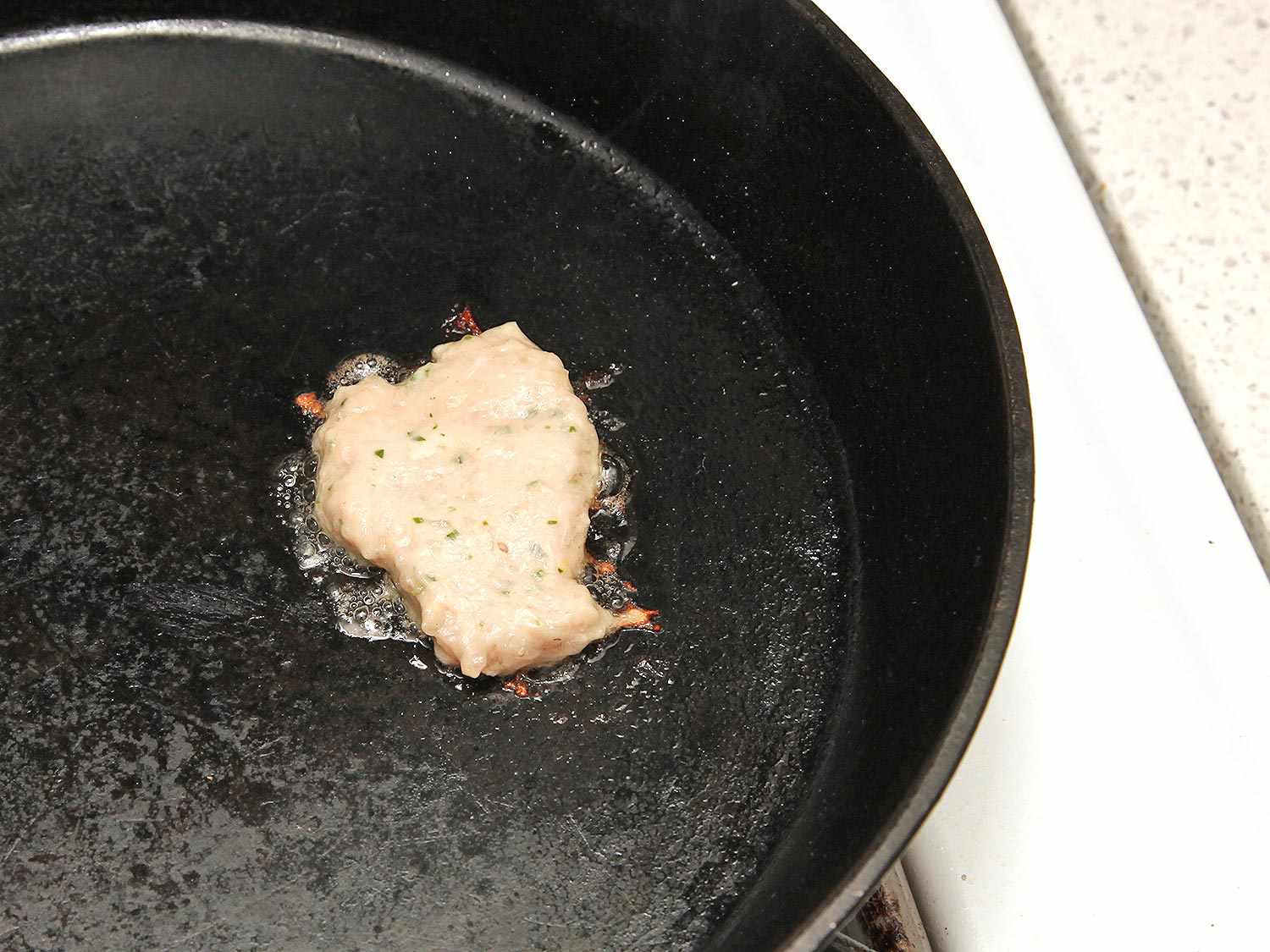 A small amount of the sausage forcemeat is cooked in a skillet to check seasoning levels.