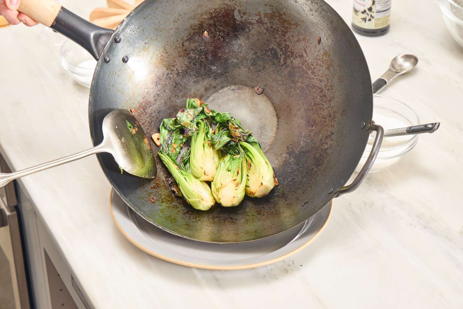 Stir-fried bok choyed being dished out from the Mammafong Pre-Seasoned Blue Carbon Steel Flat-Bottom Pow Wok