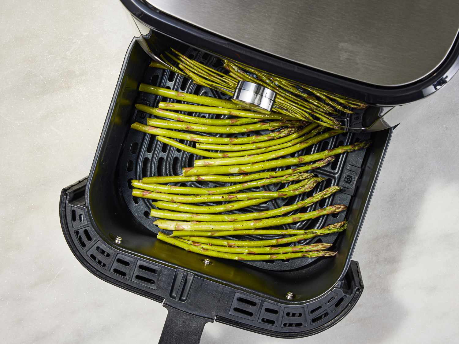Asparagus is added to the air-fryer basket.