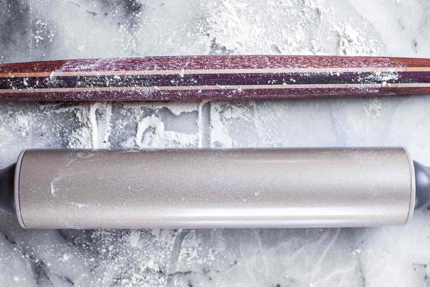 Two rolling pins on a floured marble surface