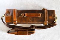 Rustic Town Genuine Leather Chef Knife Roll with straps and a handle placed on a gray surface