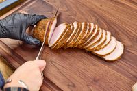 A person slices meat with the Wüsthof Classic 9 Inch Hollow Edge Carving Knife
