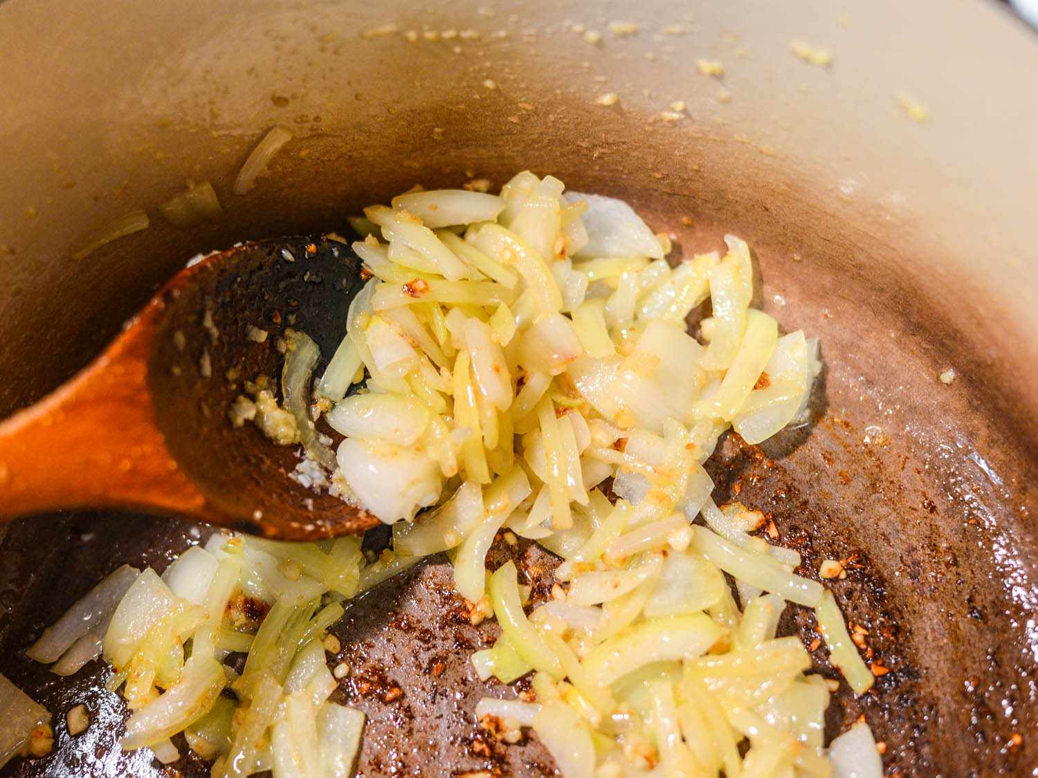 Sliced onions and minced garlic and ginger cooking in a Dutch oven.