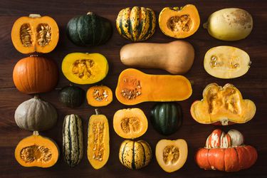 A collection of different varieties of winter squash, displayed cut-side down and cut-side up