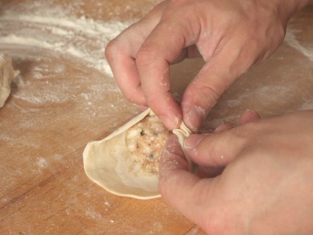 Author has started to crimp the outer edges of the dumpling wrapper.