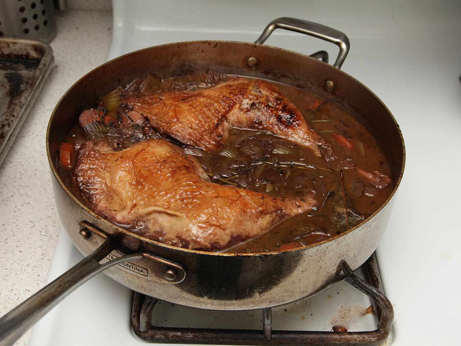 Turkey legs simmering in braising liquid.