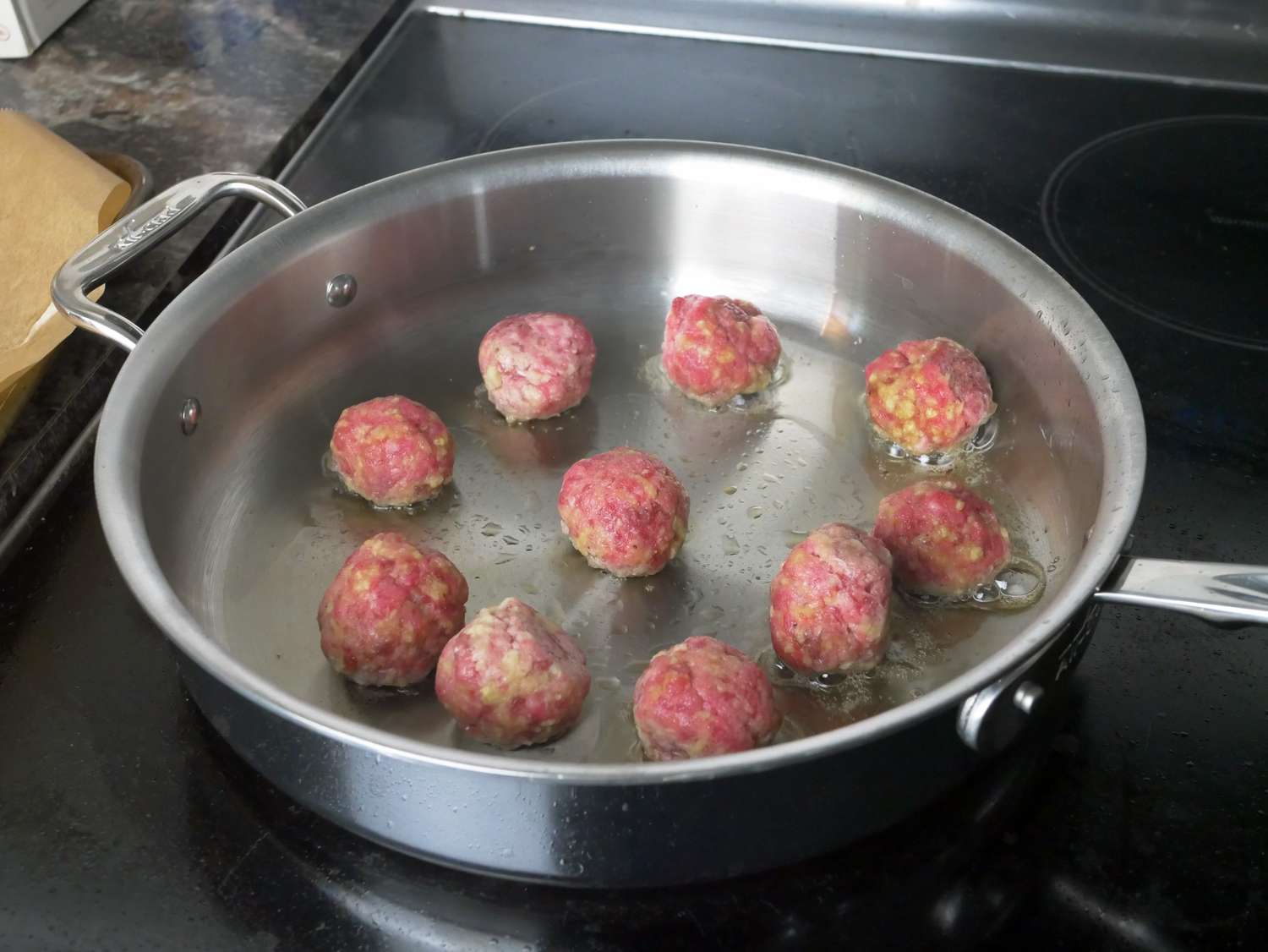 a pan with meatballs searing inside it
