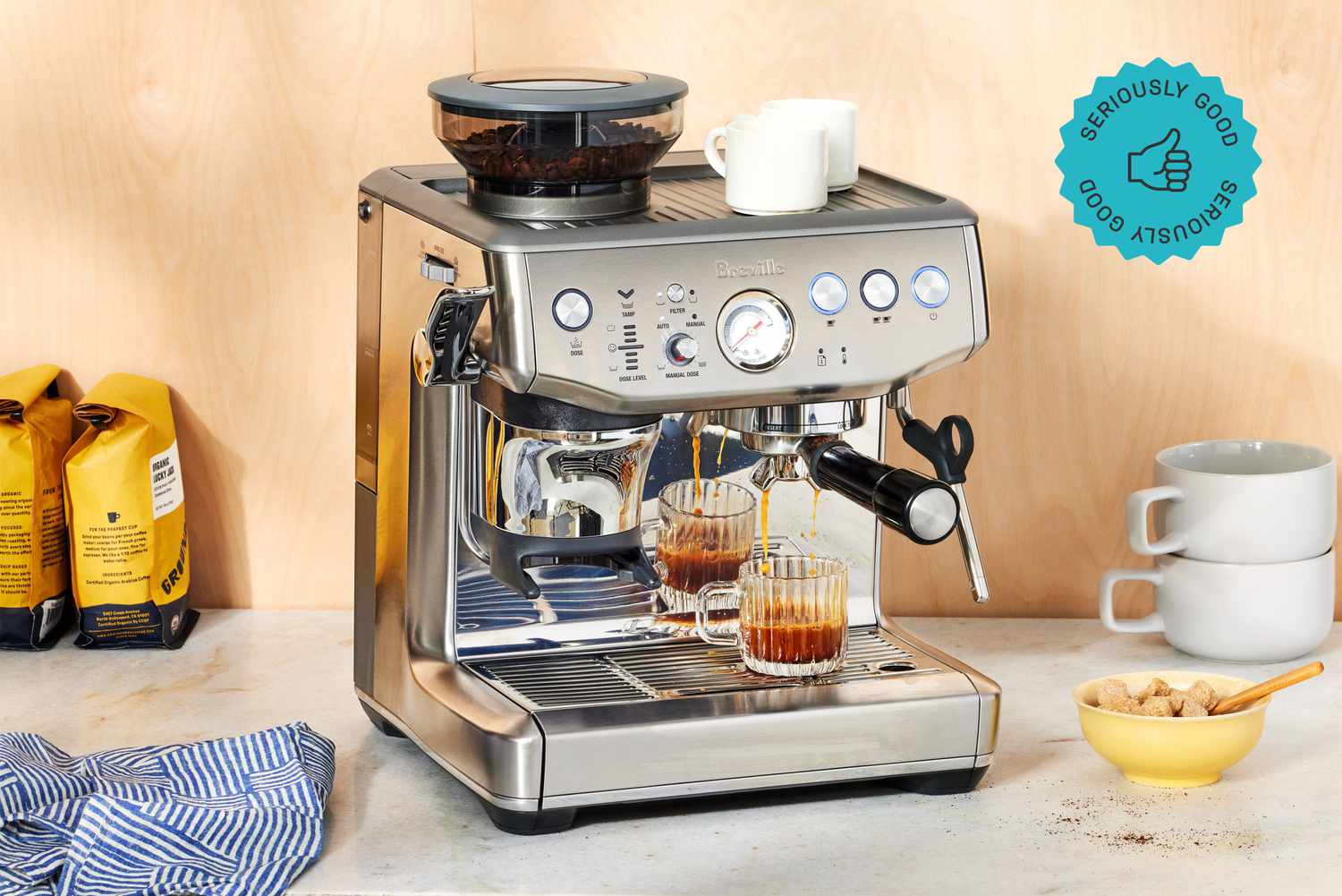 A Breville espresso machine brewing coffee into a small cup.