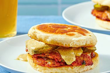 Turkey chourico smash burger on a plate with pickles and sauce between buns