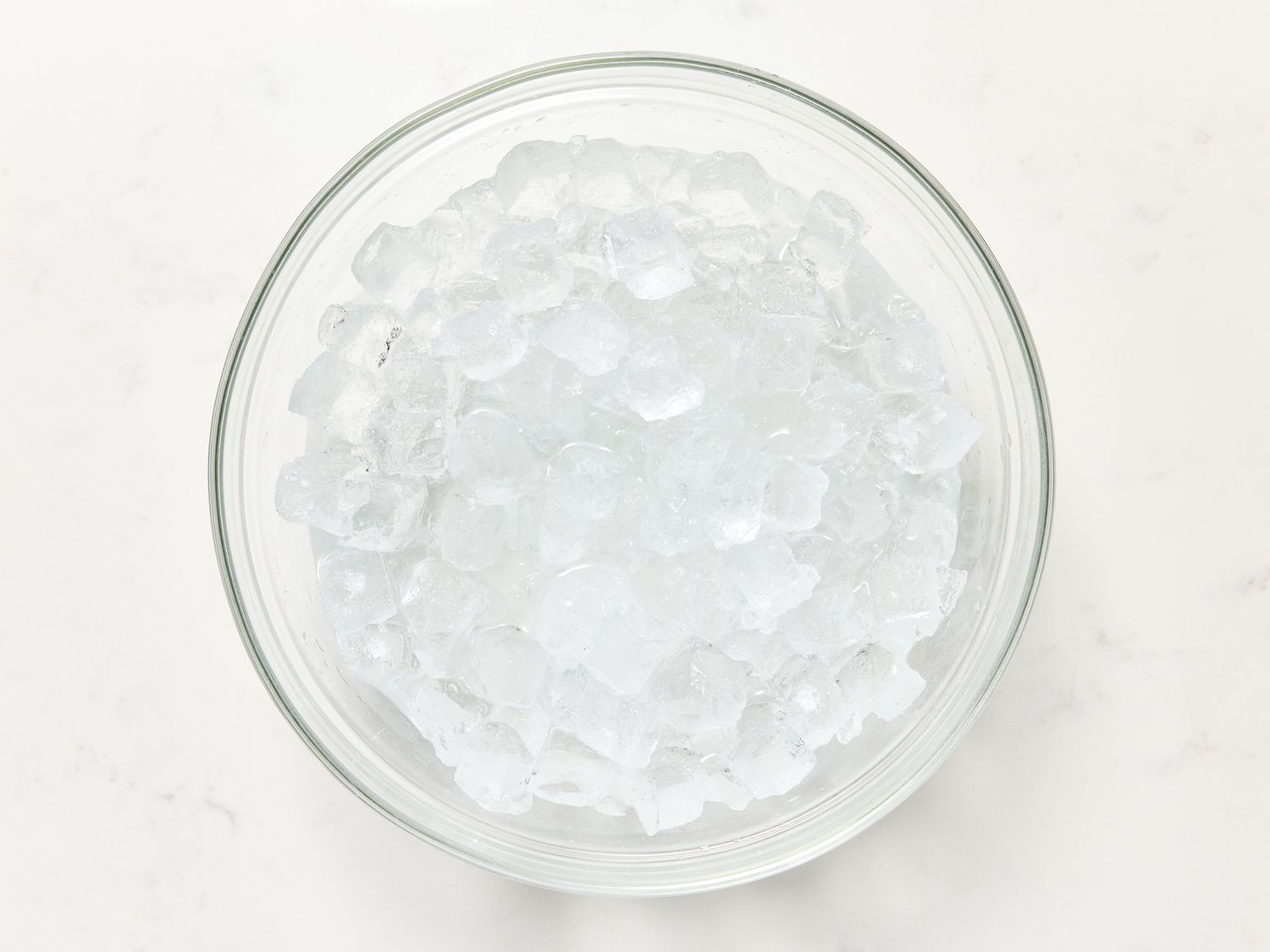 Glass bowl filled with ice cubes, on a light surface